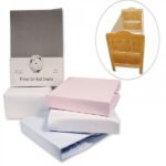 Fitted cat bed sheets in gray, pink, and white with packaging and a wooden crib in the corner.